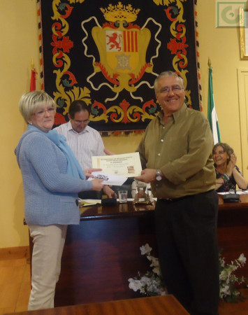 Ana Mª Garcí­a, en nombre de Timbrado Juan Manuel Román Garcí­a, recoge el tercer premio, ganado por Manuel Terrí­n, de manos de Aurelio López, de la Asociación de Vecinos Plaza de la Verdura.