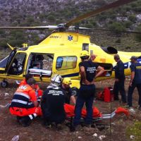 Bomberos y sanitarios atienden al accidentado para trasladarlo en helicóptero al hospital.