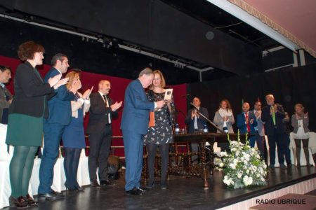 Bartolomé Pérez Sánchez de Medina recibe la insignia de Hijo Predilecto de la Villa, de manos de la alcaldesa, Isabel Gómez Garcí­a, en presencia de la corporación municipal, ante un auditorio lleno (Foto: Radio Ubrique).