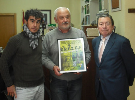 El alcalde, con el cartel del partido de fútbol, con el consejero externo del Cádiz, Miguel Cuesta, y el concejal de Deportes, Víctor Chaves.