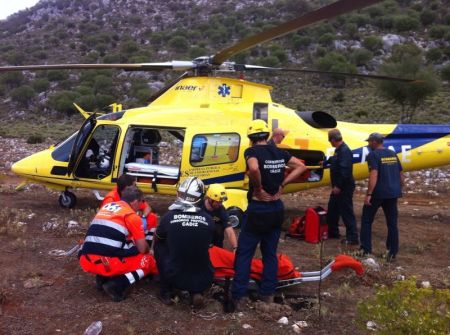 Bomberos y sanitarios atienden al accidentado para trasladarlo en helicóptero al hospital.