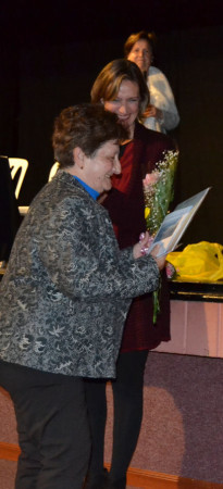 La alcaldesaentrega un ramo de flores a una de las descendientes de una componente de la directiva de Renacer.
