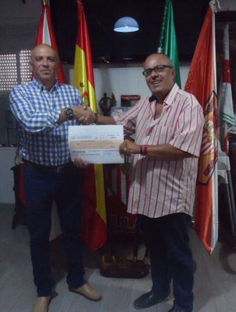 El presidente de la Peña Sevillista, Manuel Sígler, entrega el premio correspondiente a la persona que vendió la papeleta que resultó agraciada, Jesús Reina.