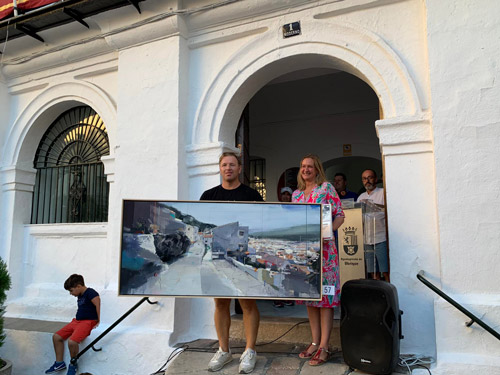 La alcaldesa entrega el premio al artista ganador, que muestra su cuadro.